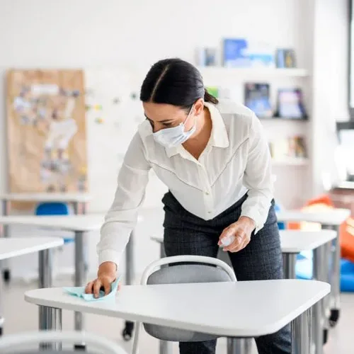 Cleaner wiping down a classroom desk
